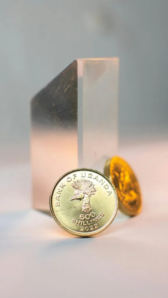 Detailed close-up of Ugandan shilling coins in a creative studio setting.